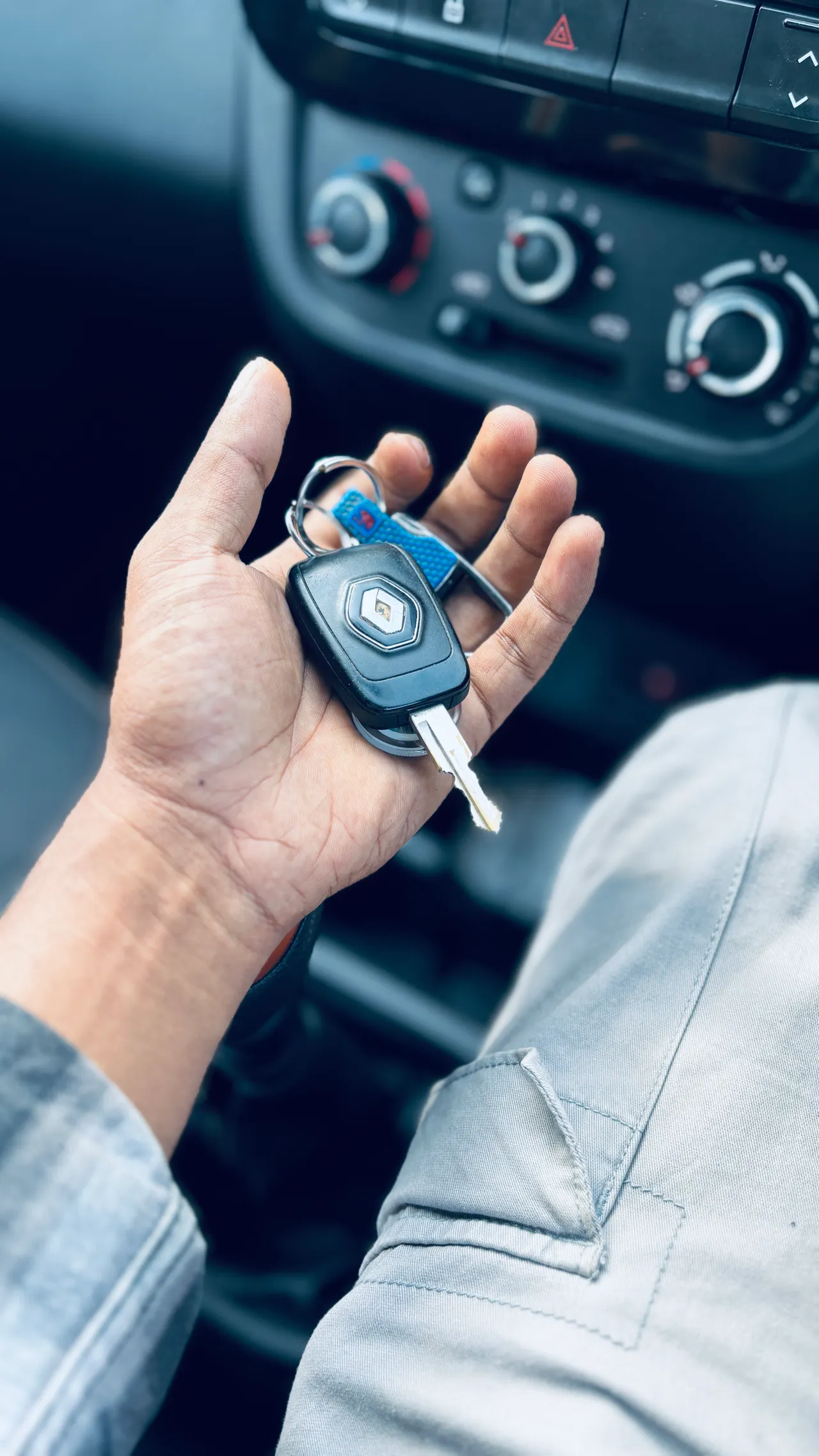 Hand übergibt Autoschlüssel im Fahrzeuginneren – Schlüsselübergabe und Schadensdokumentation bei der Autovermietung